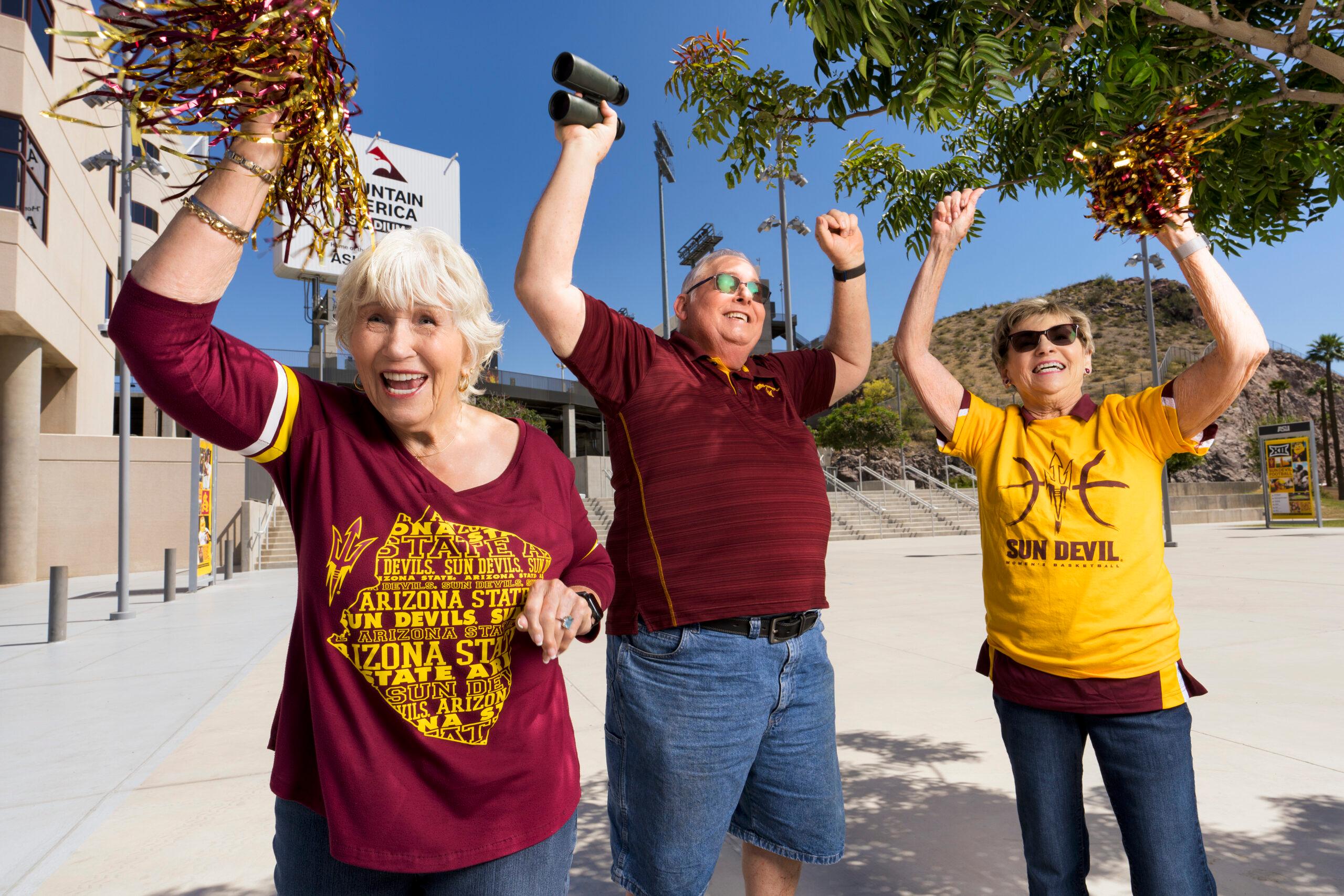 Several Mirabella at ASU residents in maroon and gold colors cheer for the Sun Devils before a game.