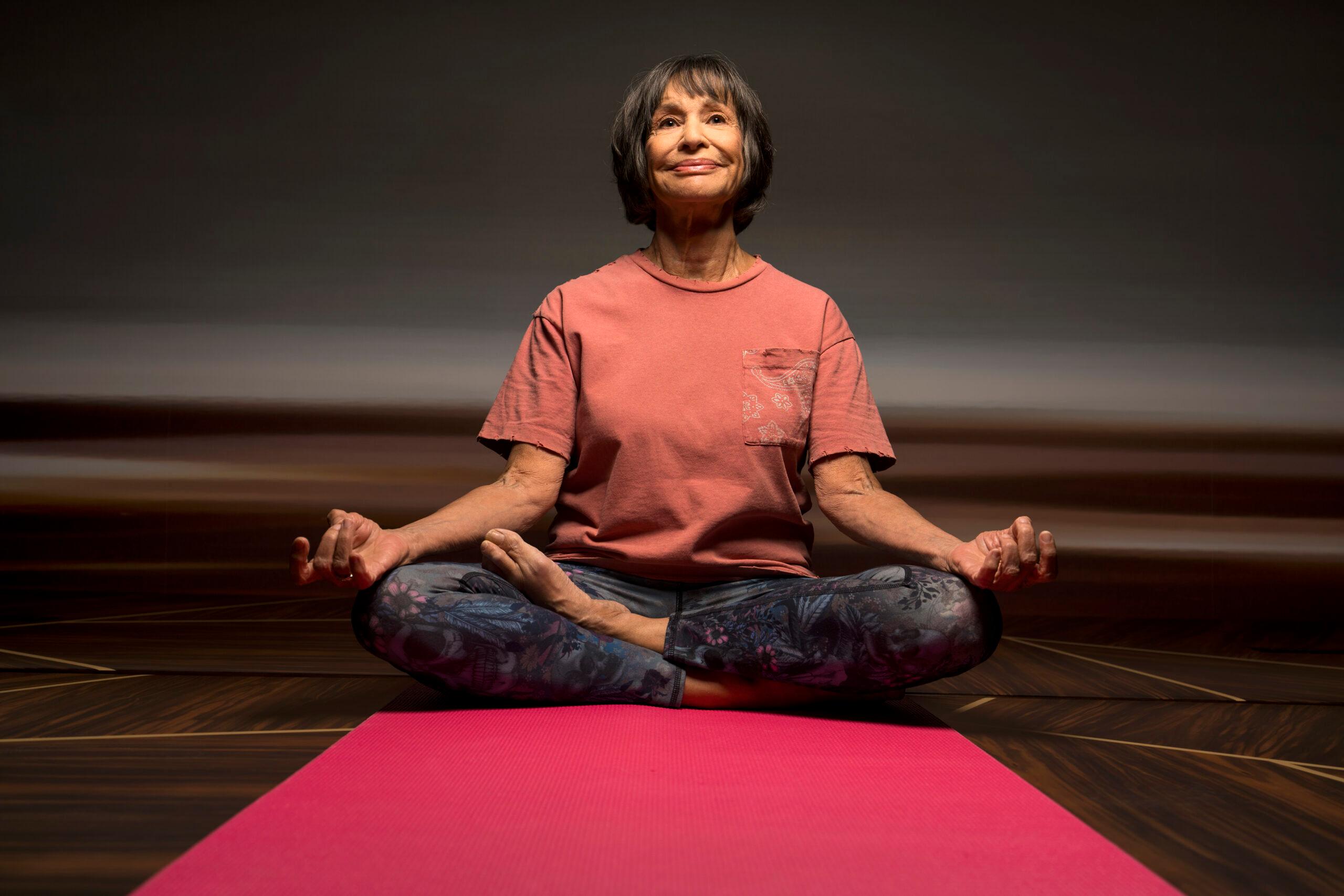 A woman sitting on a yoga mat concentrates on a yoga position.