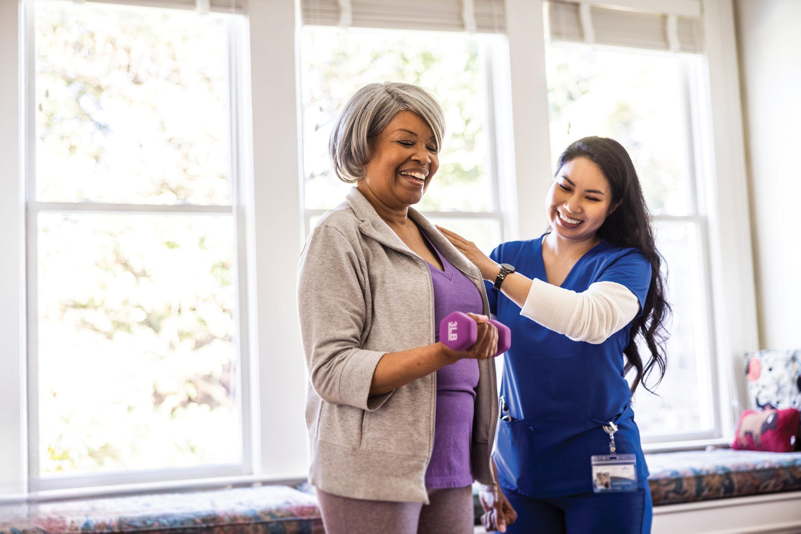 A personal trainer helps an older woman with a strength training exercise.