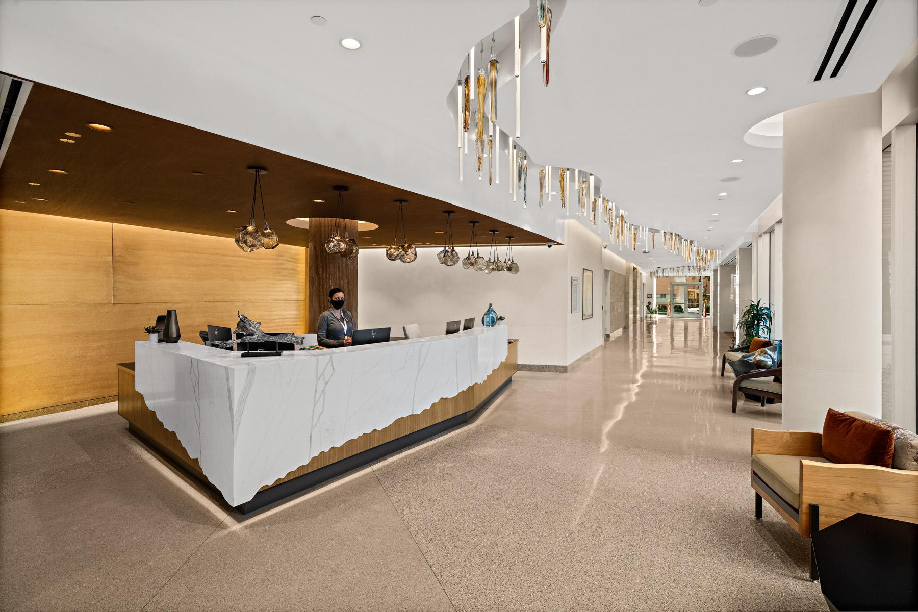 A concierge at the Mirabella at ASU front desk. A decorative chandelier spans the length of the hallway.